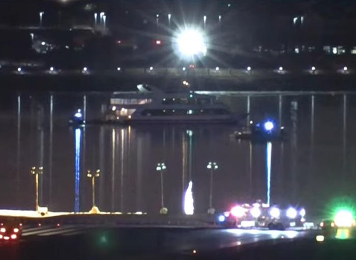 Emergency vehicles and a boat at night reflecting on water after DC American Airlines plane crash. Emergency vehicles and a boat at night reflecting on water after DC American Airlines plane crash.