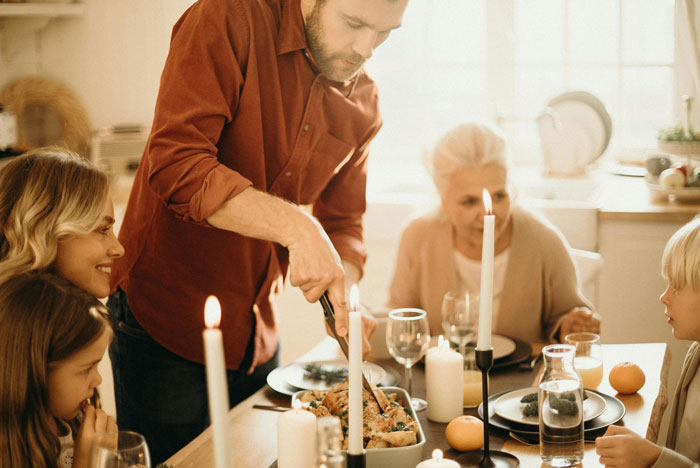 Husband serving food to family at dinner table, with wife and children, creating a warm cooking atmosphere. Husband serving food to family at dinner table, with wife and children, creating a warm cooking atmosphere.