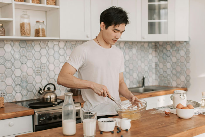Young man whisking ingredients in a modern kitchen for a cooking drama. Young man whisking ingredients in a modern kitchen for a cooking drama.