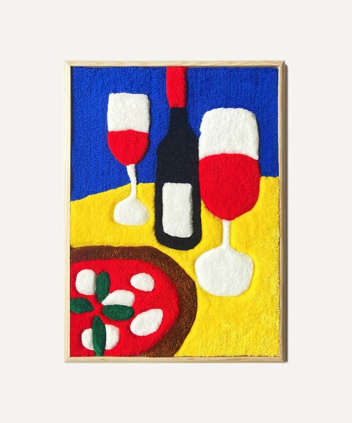 Tufted artwork with two wine glasses and a bottle on a table, featuring vibrant colors and abstract design.