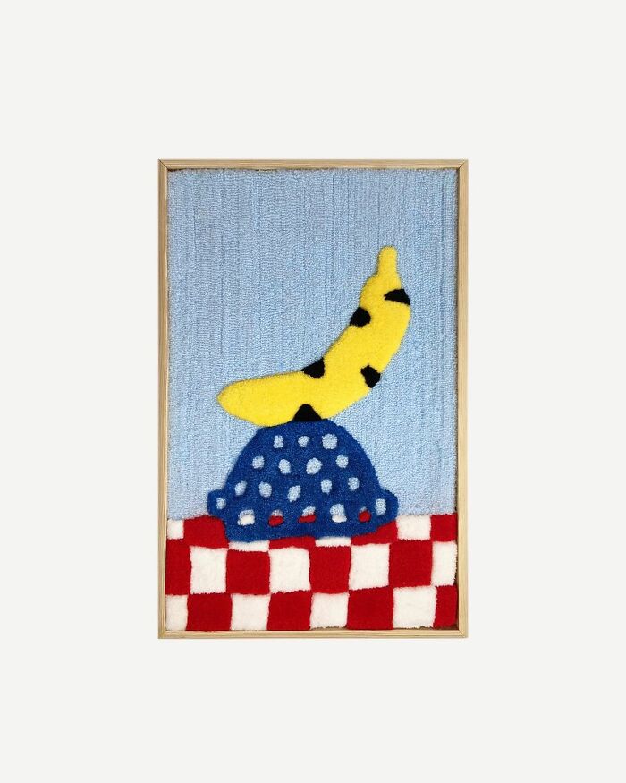 Tufted artwork featuring a colorful abstract design with a yellow banana shape on a blue and red checkered background.
