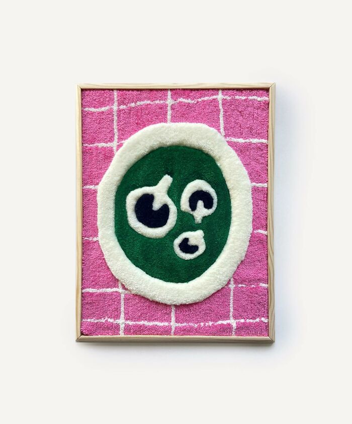 Tufted artwork featuring an abstract design in pink, green, and white, framed and displayed on a light background.