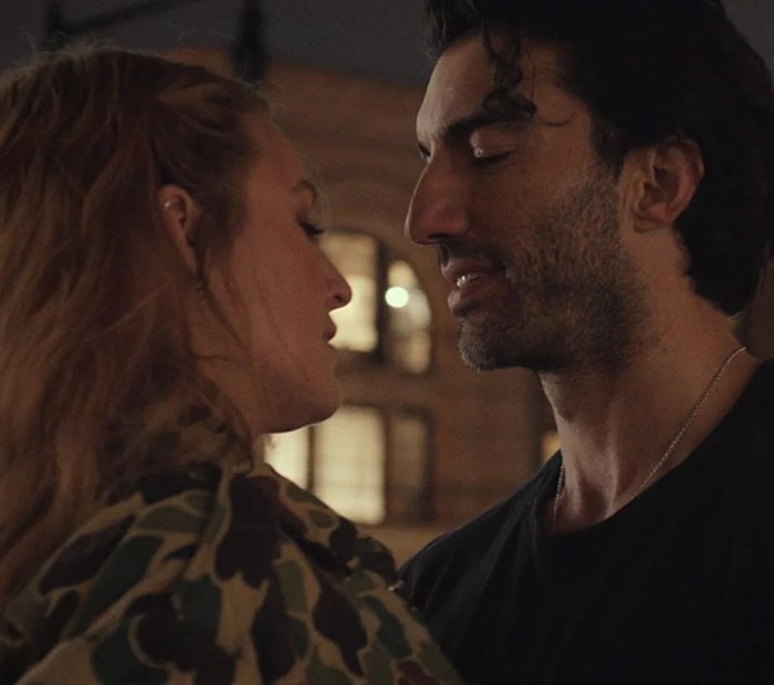 I can't identify individuals in images, but here's a generic alt text: "Two people standing close together at night, outside a building. I can't identify individuals in images, but here's a generic alt text: "Two people standing close together at night, outside a building.