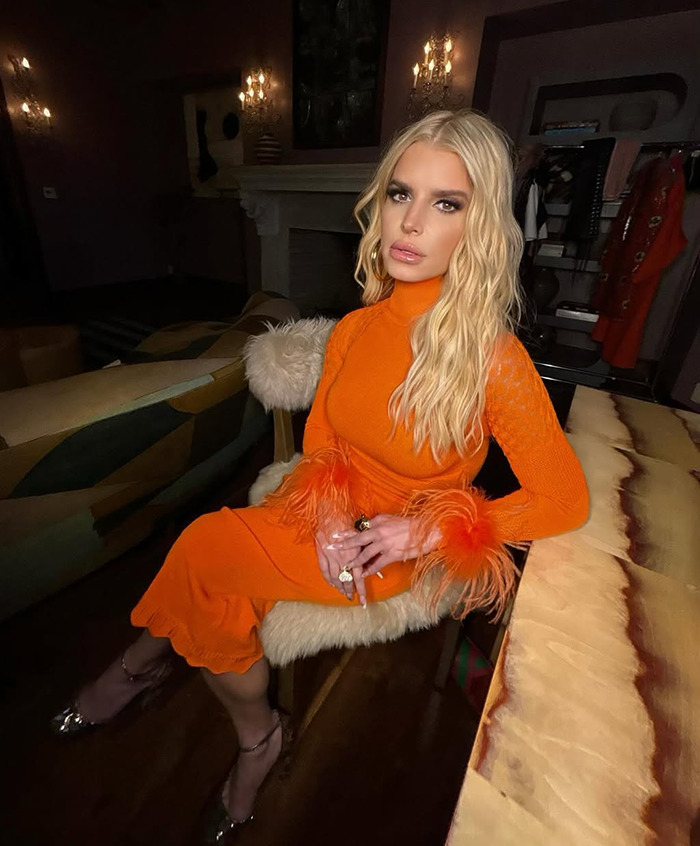 Blonde woman in an orange dress sits indoors, showcasing her "revenge body" confidently. Blonde woman in an orange dress sits indoors, showcasing her "revenge body" confidently.