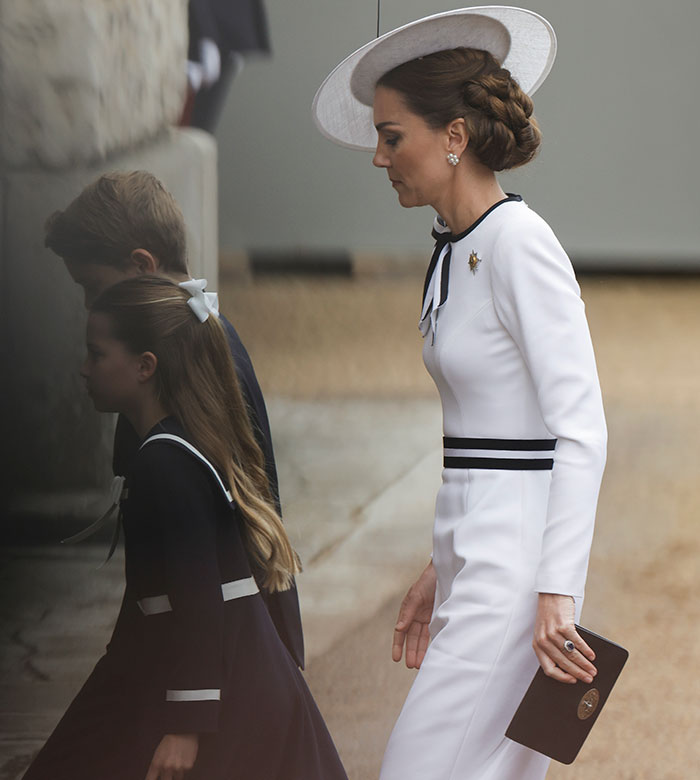 Kate Middleton in a white dress, wearing an engagement ring, walking with children. Kate Middleton in a white dress, wearing an engagement ring, walking with children.