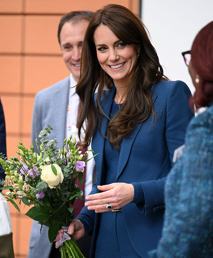 Woman in blue suit holding flowers, wearing an engagement ring. Woman in blue suit holding flowers, wearing an engagement ring.