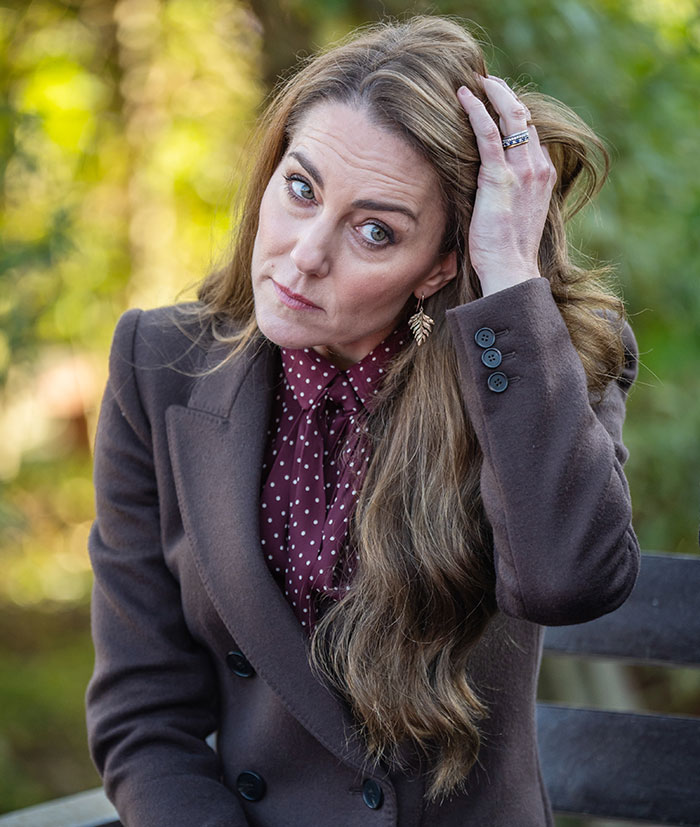 Woman in a brown coat adjusts her hair, showing an engagement ring, sparking mystery theories. Woman in a brown coat adjusts her hair, showing an engagement ring, sparking mystery theories.