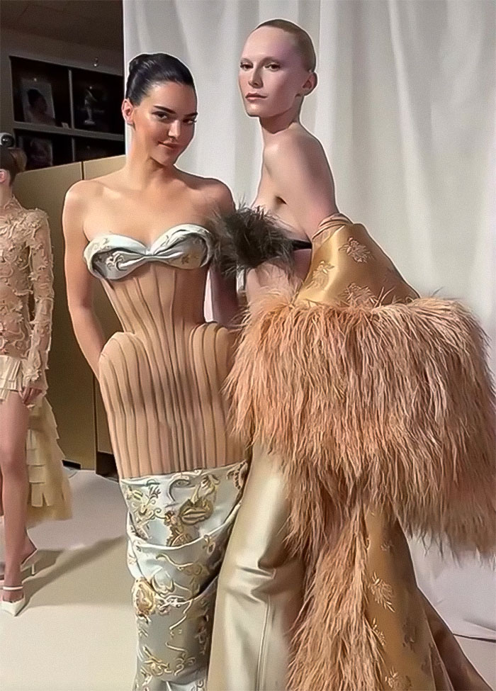Kendall Jenner in a sheer dress during Paris Fashion Week, posing with another model in a fur-adorned outfit. Kendall Jenner in a sheer dress during Paris Fashion Week, posing with another model in a fur-adorned outfit.