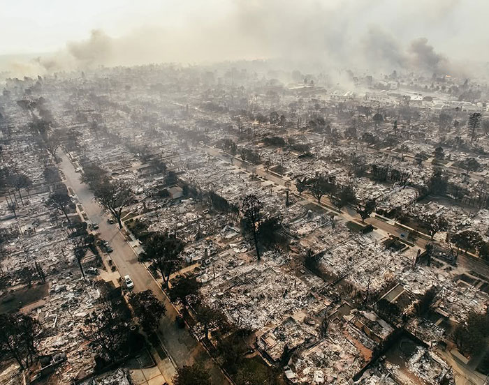 Aerial view of destruction from LA wildfires, smoke rising from burned buildings. Aerial view of destruction from LA wildfires, smoke rising from burned buildings.
