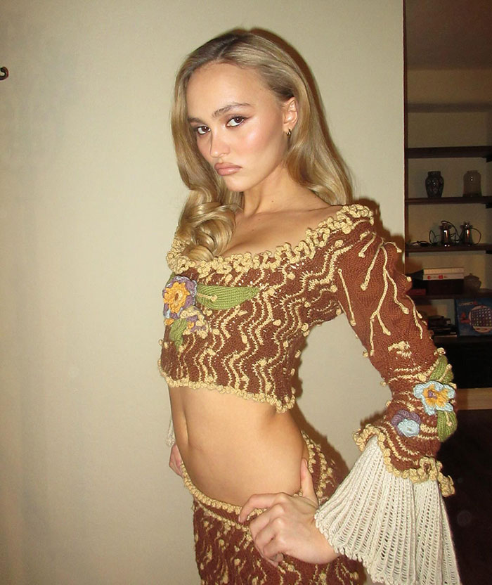 Blonde woman in a brown crochet outfit with floral details, posing indoors. Blonde woman in a brown crochet outfit with floral details, posing indoors.