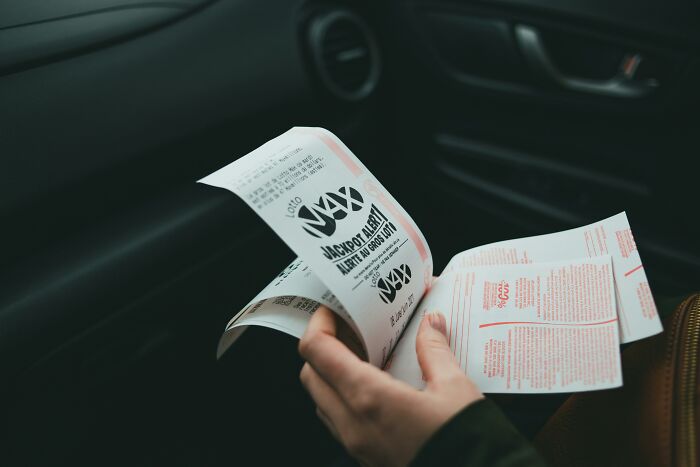 Person holding lottery tickets in a car, illustrating tips for handling lottery wins. Person holding lottery tickets in a car, illustrating tips for handling lottery wins.