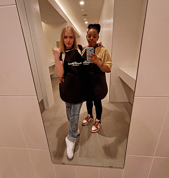 Black woman and her girlfriend posing together in a restroom mirror selfie. Black woman and her girlfriend posing together in a restroom mirror selfie.