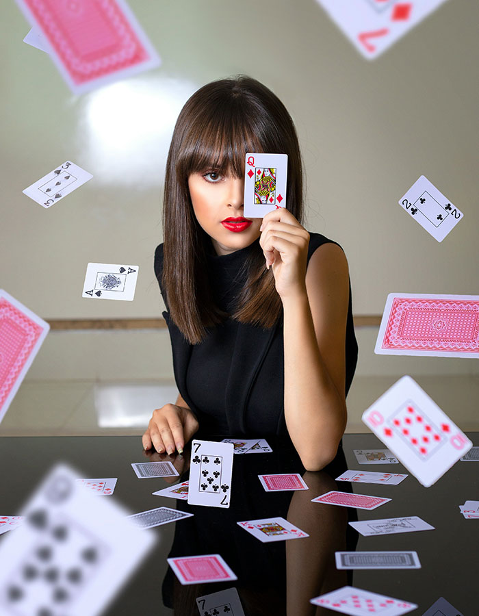 Freelance magician performing card trick, woman holding queen of hearts surrounded by floating playing cards. Freelance magician performing card trick, woman holding queen of hearts surrounded by floating playing cards.