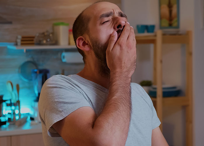 Man in kitchen yawning, contemplating decision after wife's C-section. Man in kitchen yawning, contemplating decision after wife's C-section.