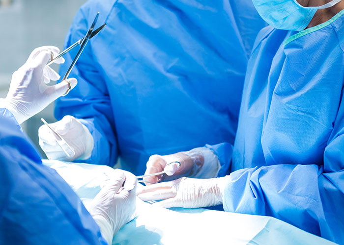 Surgeons in blue scrubs performing a C-section procedure in an operating room. Surgeons in blue scrubs performing a C-section procedure in an operating room.