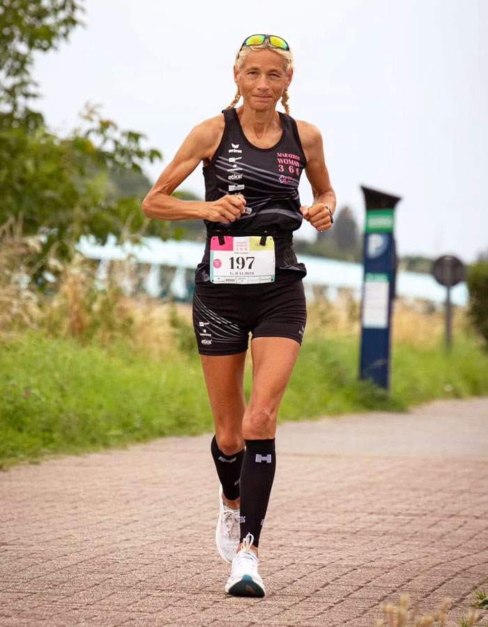 55-year-old woman running a marathon, wearing a black athletic outfit, setting a world record. 55-year-old woman running a marathon, wearing a black athletic outfit, setting a world record.