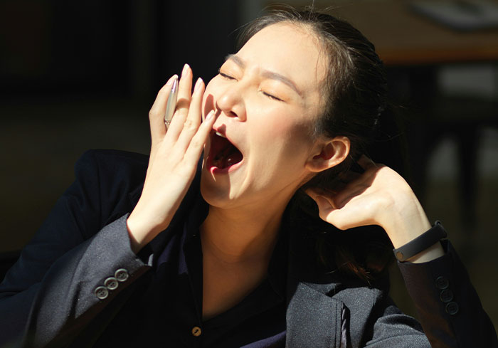 Woman yawning, covering mouth with hand, symbolizing tiredness after late-night event. Woman yawning, covering mouth with hand, symbolizing tiredness after late-night event.