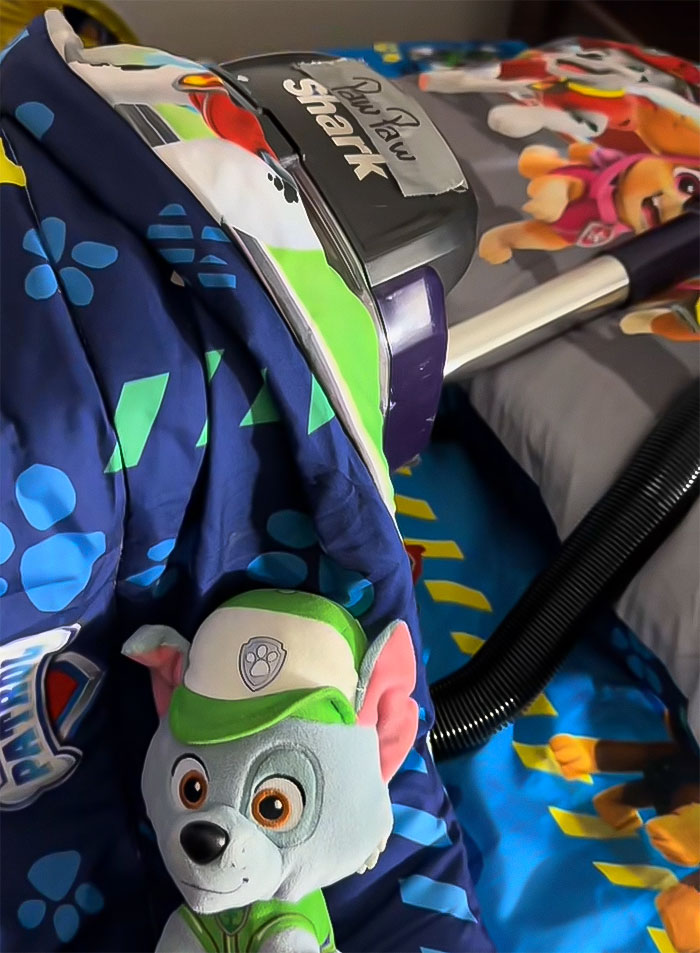 Mom vacuuming cartoon-themed bedspread; cleaning dirt thought to be on son's floor. Mom vacuuming cartoon-themed bedspread; cleaning dirt thought to be on son's floor.