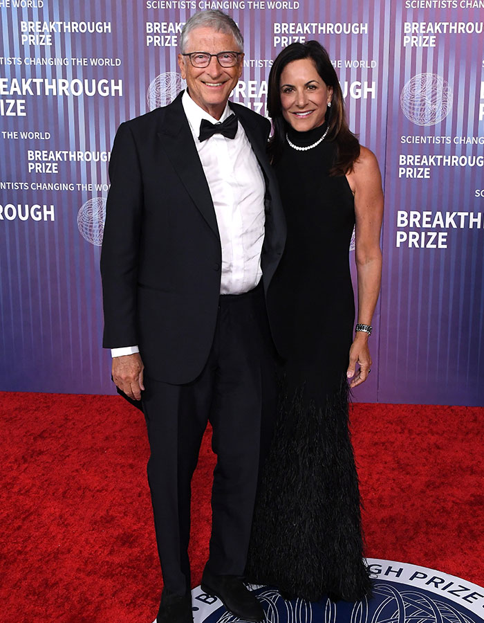 Bill Gates at a formal event on the red carpet, smiling and posing with a woman in a black gown. Bill Gates at a formal event on the red carpet, smiling and posing with a woman in a black gown.