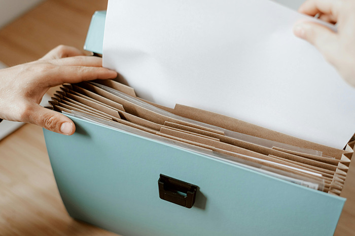 Hands sorting through documents in a blue file box. Hands sorting through documents in a blue file box.