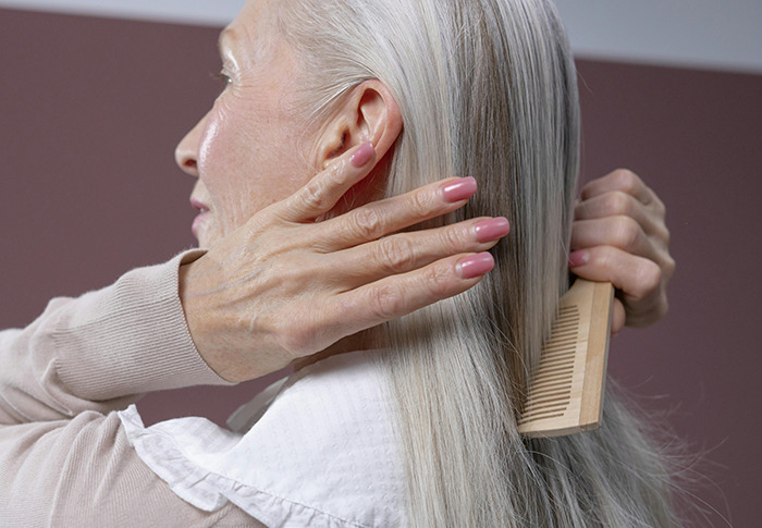 Older woman combing her long gray hair. Older woman combing her long gray hair.