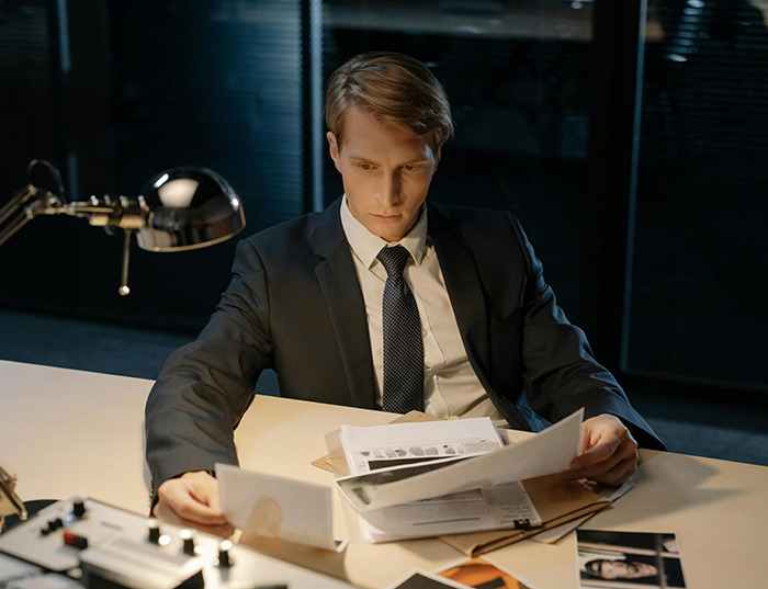 Man in suit examining documents at a desk. Man in suit examining documents at a desk.