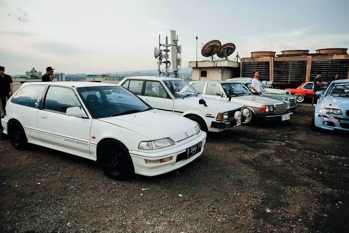 2000s teens reminiscing with vintage cars on a rooftop, capturing nostalgic vibes.