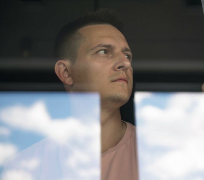 Man looking thoughtfully out a window against a cloudy sky, reflecting on secret mission in private yard. Man looking thoughtfully out a window against a cloudy sky, reflecting on secret mission in private yard.