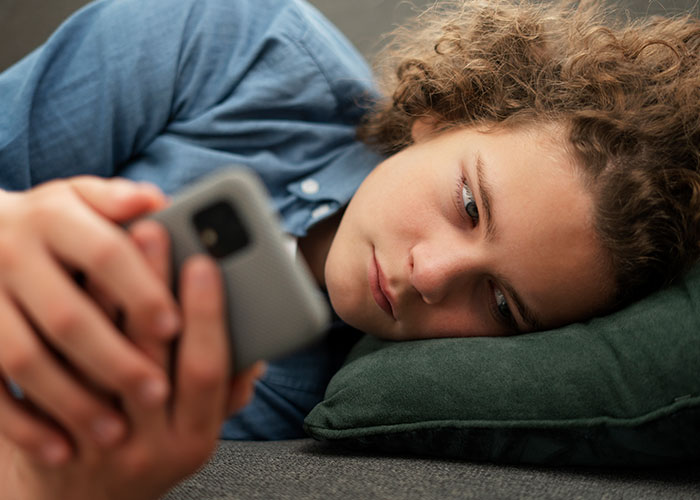 Person using a smartphone, reflecting on the post-brain rot era while lying down on a pillow. Person using a smartphone, reflecting on the post-brain rot era while lying down on a pillow.