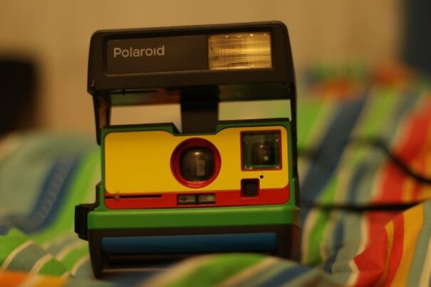 Retro Polaroid camera with colorful design on a striped background, evoking nostalgia for the good old days.
