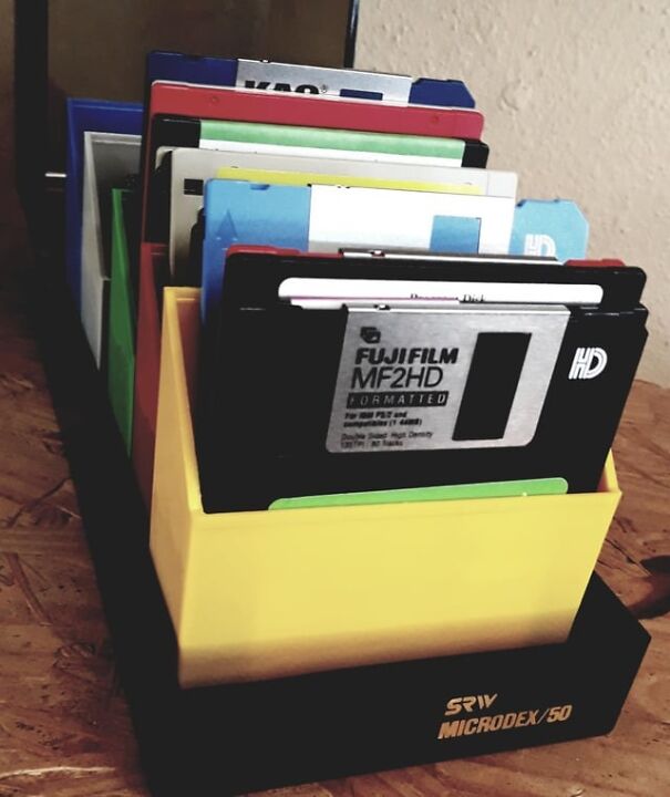 Stack of colorful retro floppy disks in a yellow holder, evoking nostalgia.