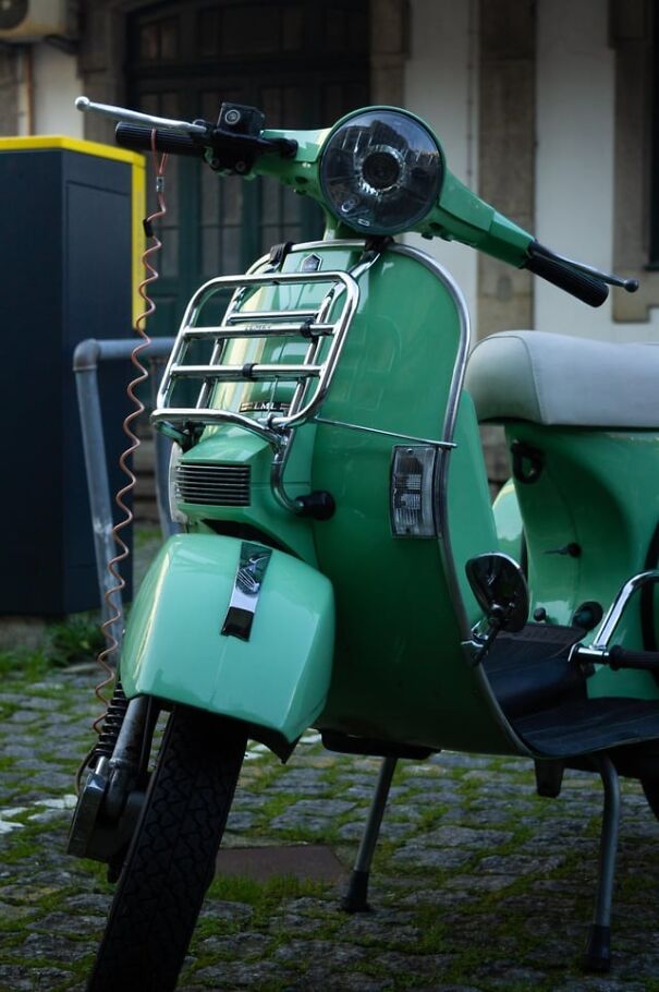 Vintage mint green scooter parked on cobblestone street, evoking nostalgia for retro finds.