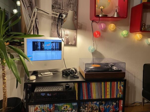 Retro setup with old computer, turntable, vinyl records, and colorful string lights, evoking nostalgia.
