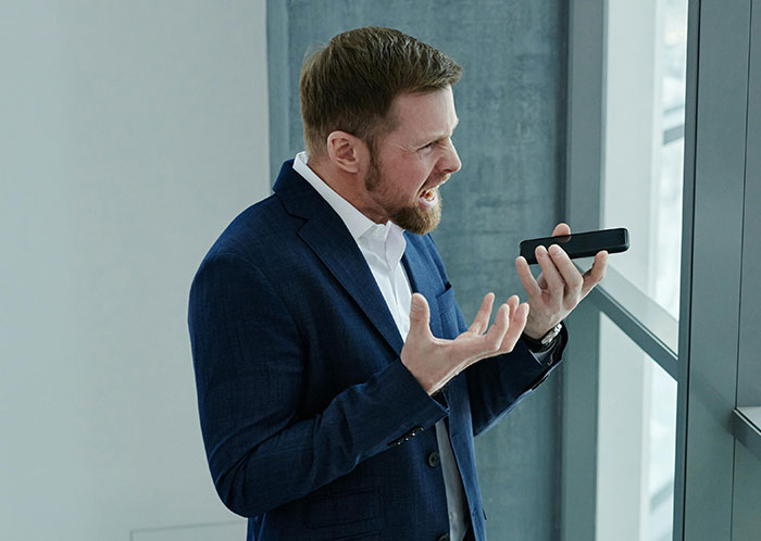 Man in a suit angrily talking on phone, expressing frustration in a modern office. Man in a suit angrily talking on phone, expressing frustration in a modern office.