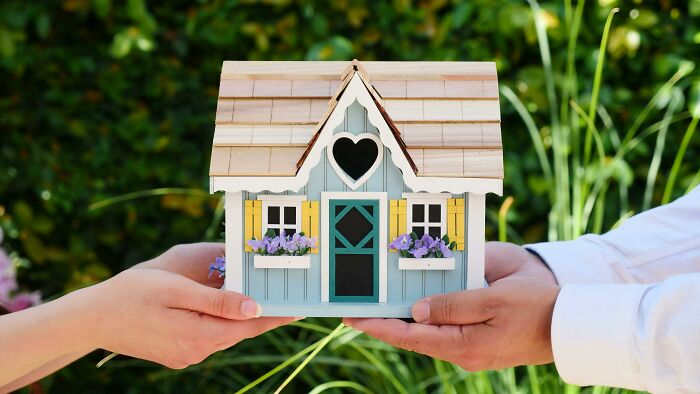 Two hands holding a model house, symbolizing ways to protect your home title from scammers. Two hands holding a model house, symbolizing ways to protect your home title from scammers.
