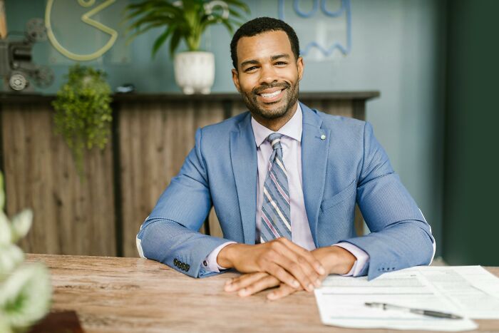 Man in a blue suit sitting at a desk, discussing ways to protect your info from scammers. Man in a blue suit sitting at a desk, discussing ways to protect your info from scammers.