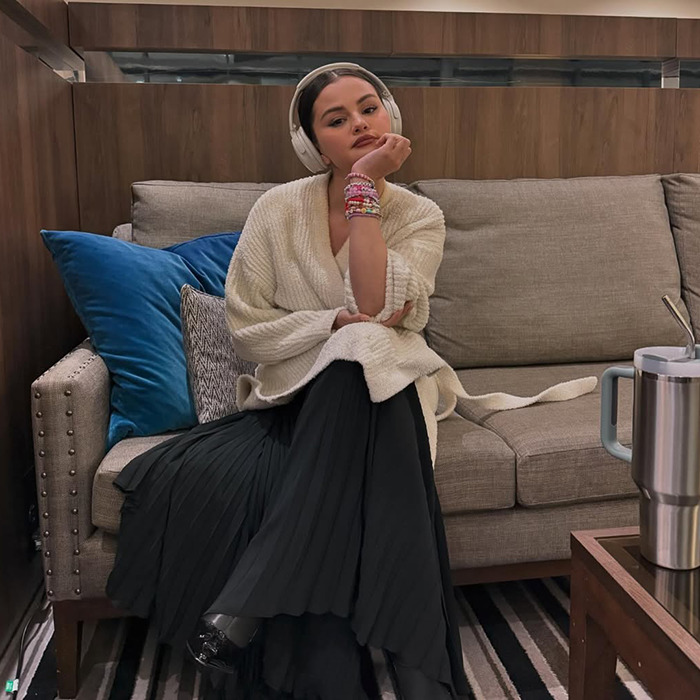 Selena Gomez sitting on a couch, wearing headphones and a cozy outfit, exuding a calm demeanor. Selena Gomez sitting on a couch, wearing headphones and a cozy outfit, exuding a calm demeanor.