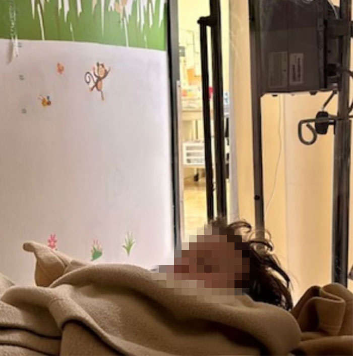 Person lying in a hospital bed, wrapped in a blanket, with a colorful mural on the wall. Person lying in a hospital bed, wrapped in a blanket, with a colorful mural on the wall.