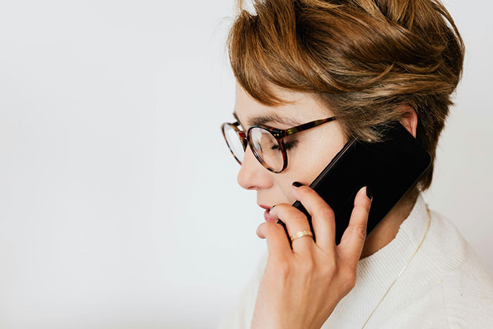 A woman with glasses discusses wedding color schemes on her phone. A woman with glasses discusses wedding color schemes on her phone.