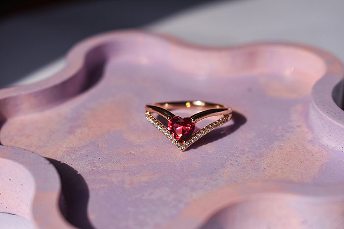 Heirloom ring with a heart-shaped red gemstone on a decorative pink tray. Heirloom ring with a heart-shaped red gemstone on a decorative pink tray.