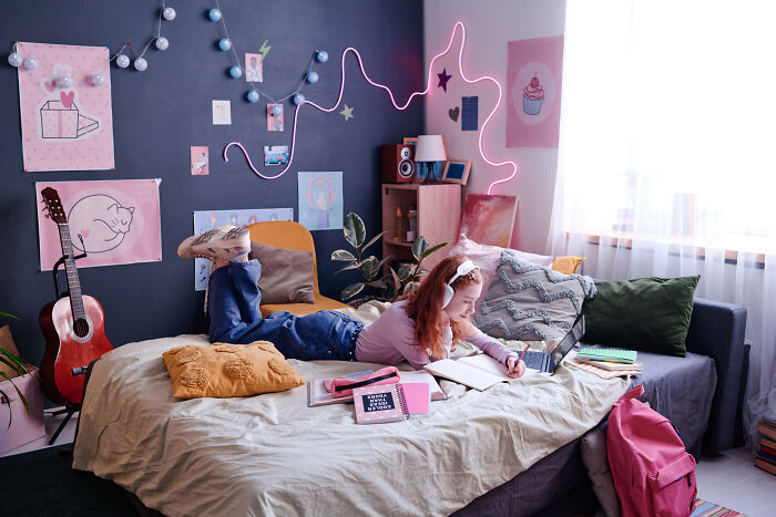 Child relaxing in a colorful family home bedroom, reading a book with wall art and a guitar nearby. Child relaxing in a colorful family home bedroom, reading a book with wall art and a guitar nearby.