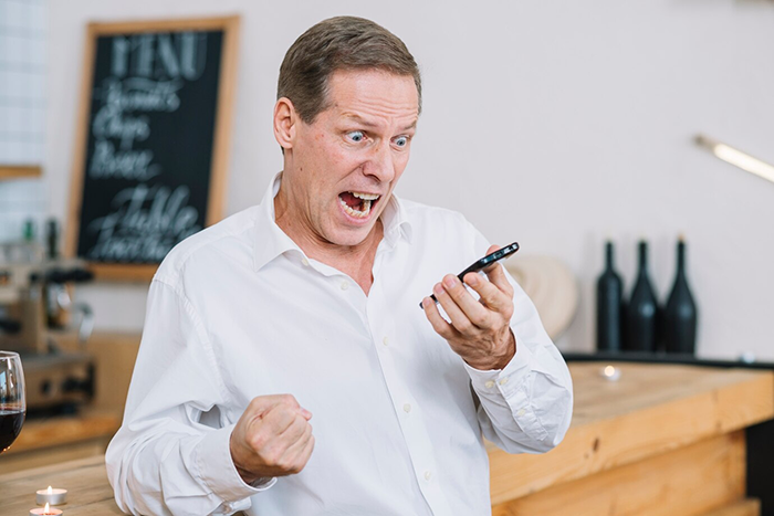 Man in a white shirt expressing excitement during a phone call in a modern cafe setting. Man in a white shirt expressing excitement during a phone call in a modern cafe setting.