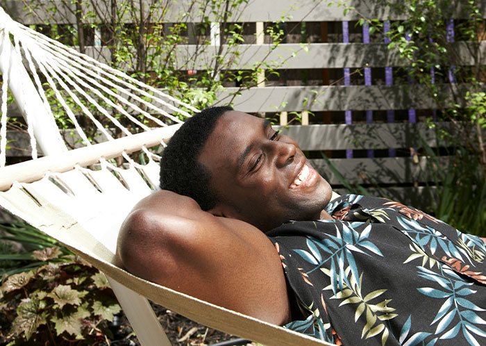 Man relaxing in a hammock, smiling under the sun at a resort, feeling satisfied after achieving petty revenge. Man relaxing in a hammock, smiling under the sun at a resort, feeling satisfied after achieving petty revenge.