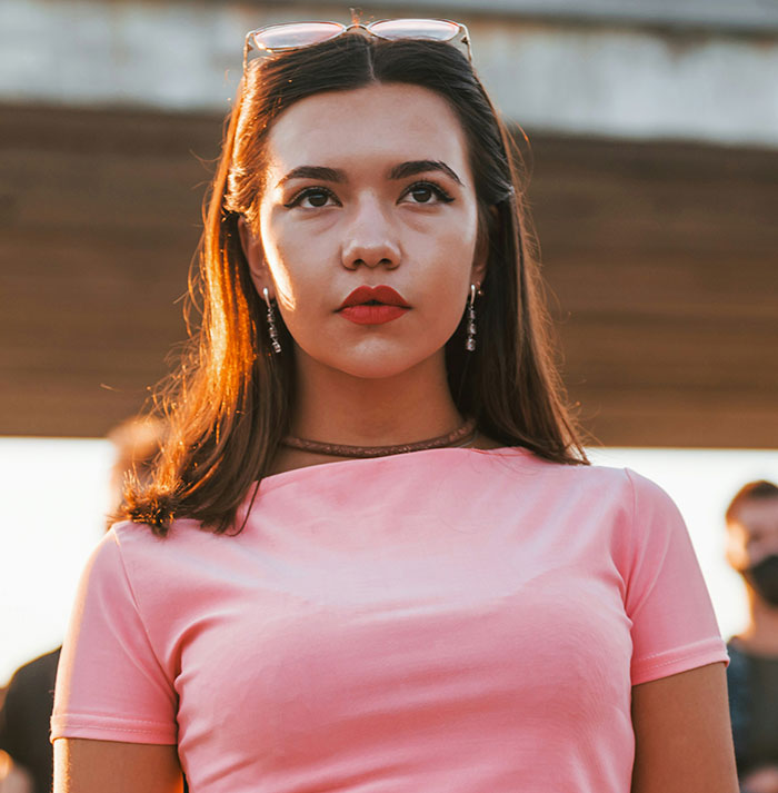 Teen in a pink shirt looking contemplative, with her hair down, outside on a sunny day. Teen in a pink shirt looking contemplative, with her hair down, outside on a sunny day.