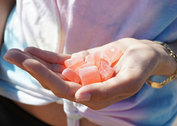 Hand holding pink gummy snacks, related to vegetarian food situation. Hand holding pink gummy snacks, related to vegetarian food situation.
