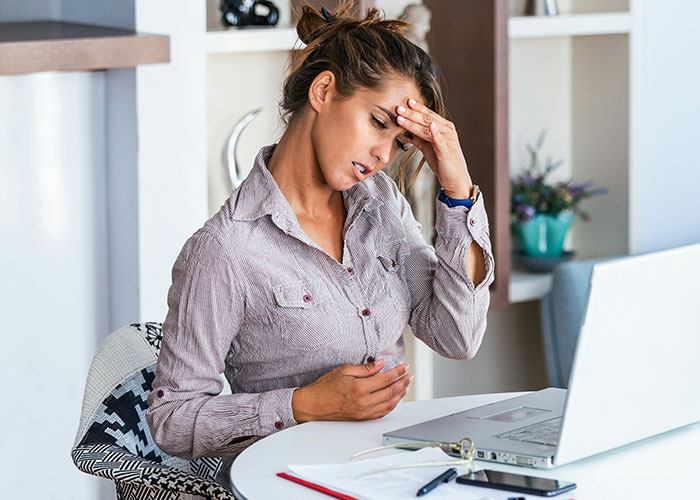 Woman in distress at a desk, possibly feeling unwell, related to vegetarian food theft at workplace. Woman in distress at a desk, possibly feeling unwell, related to vegetarian food theft at workplace.
