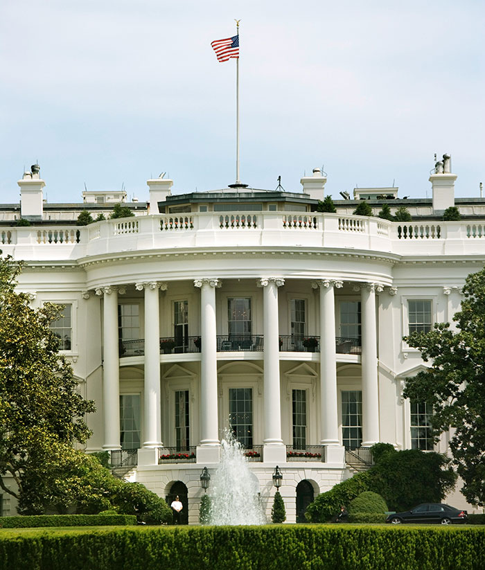 White House exterior with American flag flying on top, symbolizing political leadership. White House exterior with American flag flying on top, symbolizing political leadership.