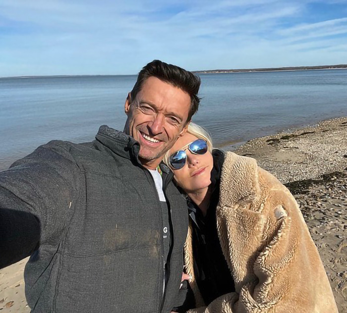 Deborra-Lee Furness and Hugh Jackman smiling on a beach, wrapped in a cozy coat. Deborra-Lee Furness and Hugh Jackman smiling on a beach, wrapped in a cozy coat.