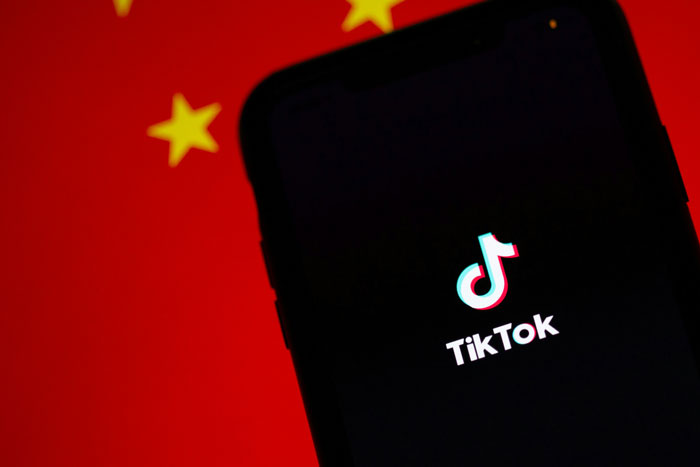 TikTok app on smartphone screen against Chinese flag backdrop. TikTok app on smartphone screen against Chinese flag backdrop.
