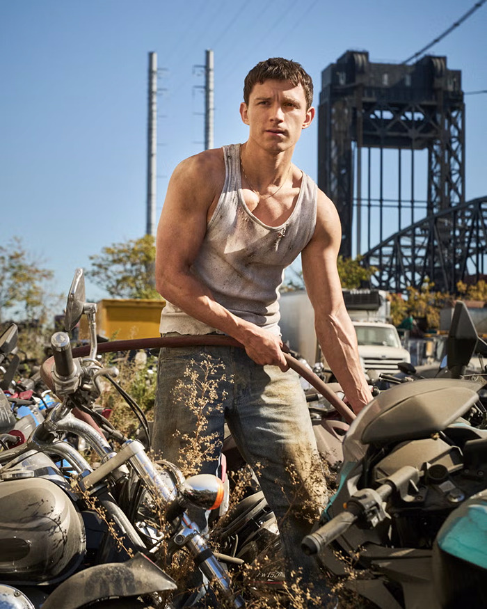 Tom Holland in a white tank top surrounded by motorcycles, urban backdrop, embodying a rugged style. Tom Holland in a white tank top surrounded by motorcycles, urban backdrop, embodying a rugged style.